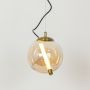 A round amber glass pendant light with a tubular LED inside glowing brightly against a white background in a simple modern design with warm light on.