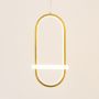 Gold and white metal oval hanging light glowing gently on white background for stylish contemporary wall decor.
