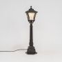 Classic solar pillar lamp post glowing warmly with clear glass shade and black metal base for outdoor lighting.