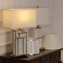 White shade marble and gold rectangular base table lamp on wooden sideboard with light on for elegant modern décor.