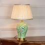 Green ceramic table lamp with floral bird artwork brass base and pleated fabric shade placed on white background for product display.