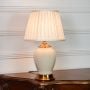 Ivory ceramic table lamp with glossy finish gold metal base and pleated fabric shade displayed cleanly on white background.
