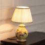 Delicate floral ceramic table lamp with gold detailing and soft white shade glows warmly enhancing interiors with vintage-inspired elegance.