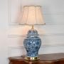 Blue white ceramic table lamp featuring intricate floral artwork brass base and fabric shade displayed on white background.
