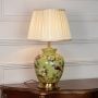 Green ceramic table lamp featuring bird and flower detailing brass metal base and pleated fabric shade on white background.