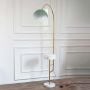 Modern floor lamp with curved gold metal stand white marble base and dome shade styled on white background interior decor.
