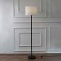 Sleek black floor lamp with off-white lampshade placed on a clean white background enhancing its minimalistic style.