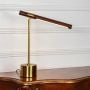 Gold metal desk lamp featuring wooden light bar adjustable arm and solid round base displayed cleanly on white background.