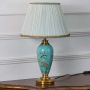 Set of turquoise and green ceramic lamps with gold bases and pleated white shades turned on together spreading warm soft glow for refined interiors.