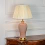 Pink ceramic table lamp featuring textured glaze finish gold metal base and pleated fabric shade displayed on white background.