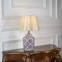 Patterned ceramic table lamp with beige shade glowing softly on white background for modern home lighting decor.