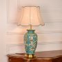 Teal ceramic table lamp featuring detailed floral motifs gold metal base and fabric shade displayed cleanly on white background.