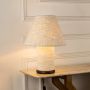 Textured table lamp illuminated on white background casting soft warm glow and showcasing woven shade elegant home Decor lighting.