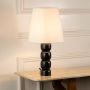 Stylish table lamp with sculpted black metal base and white shade displayed on console table for modern luxury home decor lighting.
