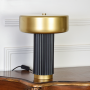 Table lamp placed on white background without light revealing clean lines gold top and black fluted base ideal for modern decor styling.