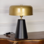 Table lamp on white background with light off presenting gold top black base and minimalist profile ideal for contemporary interiors.