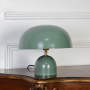 Table lamp powered off on white backdrop revealing green dome shade rounded base clean lines and contemporary form for bedside or console use.