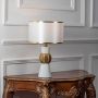 White and gold table lamp with textured golden sphere base turned on against a white background.