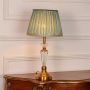 Glass and gold metal table lamp featuring pleated teal fabric shade and crystal clear stem displayed on white background.