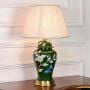 Green ceramic table lamp featuring floral butterfly design gold metal base and pleated fabric shade displayed on white background.