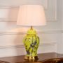 Yellow ceramic table lamp featuring bamboo bird hand painting gold metal base and fabric drum shade on white background.