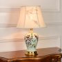 Mint green ceramic table lamp featuring bird floral hand painting gold metal base and fabric shade on white background.
