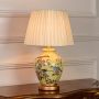 Yellow ceramic table lamp featuring floral bird hand painting gold metal base and pleated fabric shade on white background.
