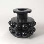 Detailed view of black ceramic vase showing the reflective spherical surface and high-gloss sculptural design.