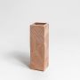 A modern brown geometric vase photographed on a white background showcasing its textured surface and sleek tall shape for stylish decor.