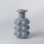 A grey designer vase with raised sphere accents displayed on a clean white background showcasing its bold geometric modern style in a minimal way.