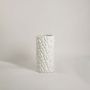 A modern white cylindrical vase with a woven texture shown on a clean white background offering a simple and elegant presentation.