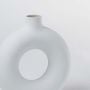 Closeup of white ceramic vase with round hollow center – elegant minimalist vase for home decoration.