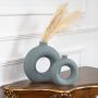 Elegant green ceramic donut vase styled with dried stems placed on classic wooden console for modern home decor display.