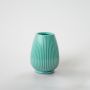 Aqua ribbed vase placed on a white background with light reflection showing its glossy ceramic finish.
