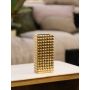 Gold geometric ceramic vase styled on a white surface with patterned backdrop adding a luxe metallic accent to living room shelf or console decor.