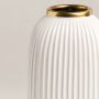 Closeup view of white ceramic vase showcasing fine ribbed texture and shiny gold rim for a modern artistic appeal.