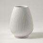 Classic ribbed white ceramic vase displayed on white background perfect for flowers and table decor.