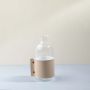 Clear glass vase with beige leather wrap and brass detail white background image perfect for elegant table decoration.
