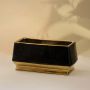 Sleek black rectangular ceramic vase with reflective golden edges captured from a side angle highlighting its bold contrast and luxurious shine.