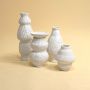 Collection of white ceramic vases with sculptural designs displayed elegantly to highlight their handcrafted textures and artistic shapes.