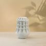 Handcrafted white ceramic vase illuminated on a white background showing artistic geometric details and smooth matte texture.