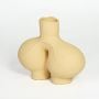 Beige ceramic sculptural flower vase with central hollow design for shelf styling and home decor display.