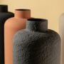 Closeup of textured ceramic vase with rough matte finish highlighting handcrafted decor detail for modern interior styling.