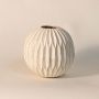 Round carved vase displayed on a clean white background showcasing artisan craftsmanship and textured surface.
