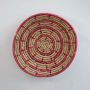 Round pink and beige woven basket wall plate displayed against a clean white background highlighting its texture.