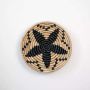 Round jute woven wall basket decor in beige and black rustic handmade star pattern boho wall art accent piece for interiors.