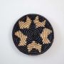 Round wicker wall decor basket handmade with natural fiber in black and beige tribal star design.