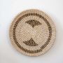Round handwoven decorative wall plate in beige and black spiral pattern for living room and home interiors.