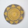 Round wicker wall plate handmade with yellow navy and beige woven pattern ideal for boho style wall decoration.