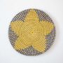 Round wicker wall plate handmade with yellow navy and beige woven star pattern ideal for boho wall decoration.